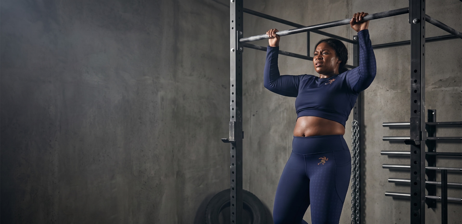 Founder of Big Belly Athletics doing a pull-up in navy athletic gear